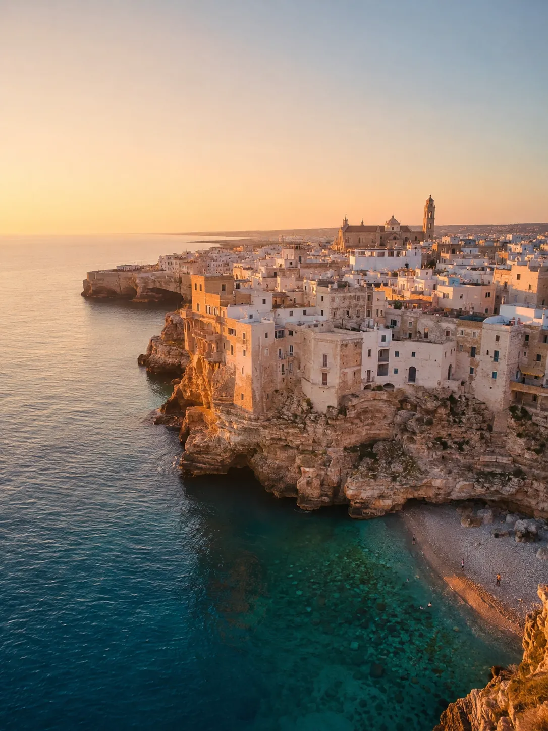 Picturesque coastal town built on rugged cliffs overlooking the sea at sunset.